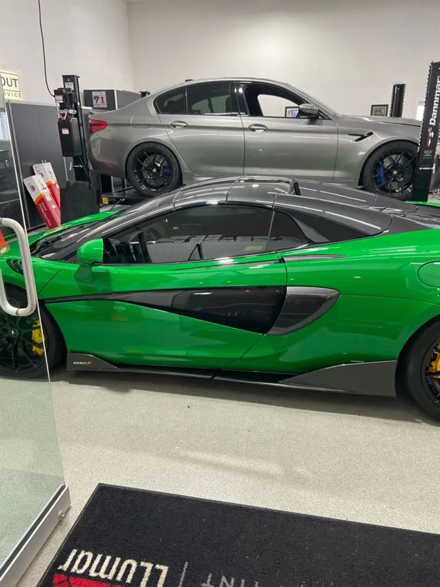 Green McLaren in the shop next to an Alfa Romeo