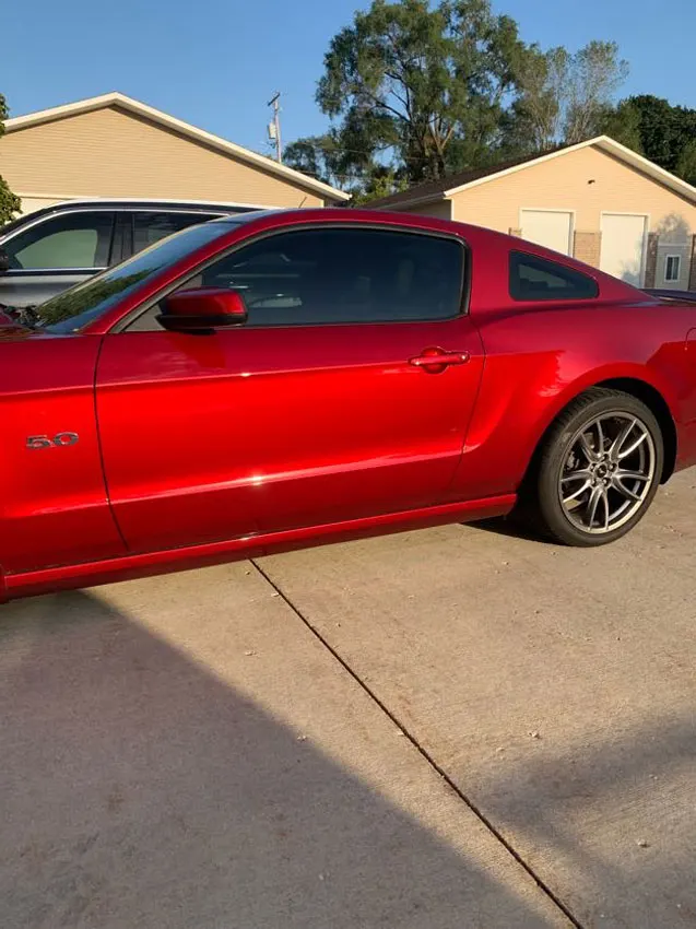 Red Mustang with tinted windows in the driveway